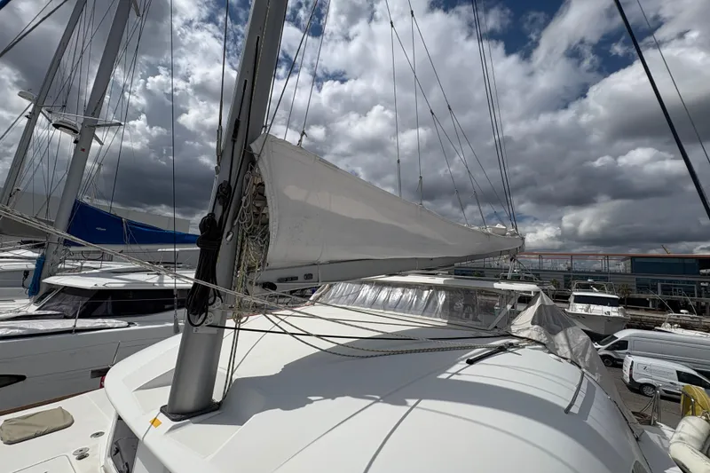 Slide: The Image of 2004 Lagoon 380 catamaran with sails, docked under cloudy skies. - 11