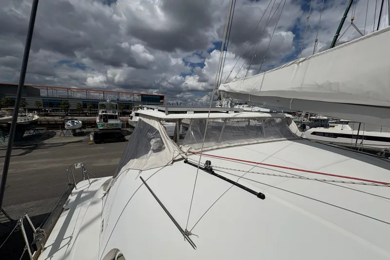 Slide: The Image of 2004 Lagoon 380 catamaran docked under cloudy skies at a marina. - 12