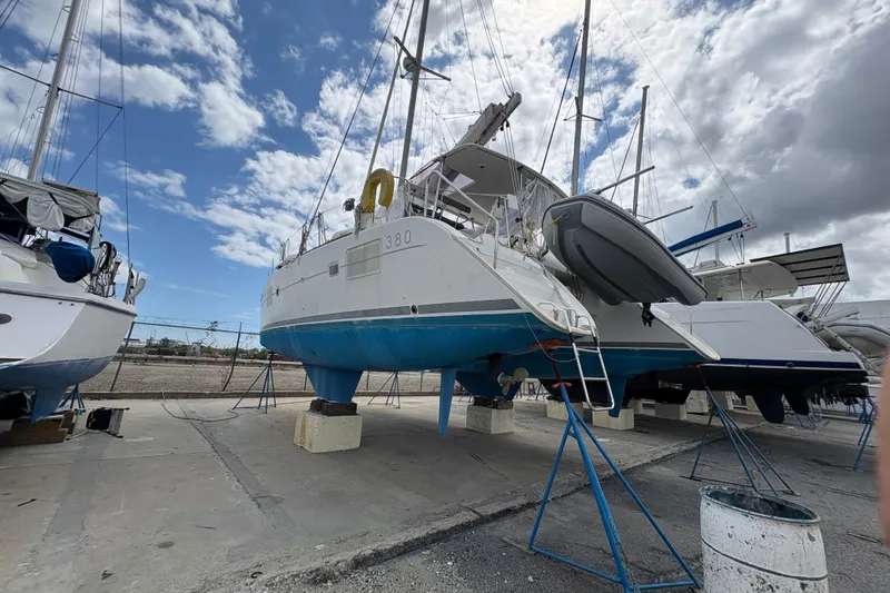 Slide: The Image of 2004 Lagoon 380 catamaran on dry dock under a partly cloudy sky. - 2