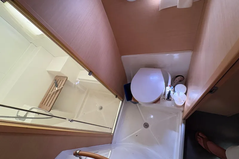 Slide: The Image of Compact bathroom in a 2004 Lagoon 380 catamaran, featuring a shower and toilet. - 23