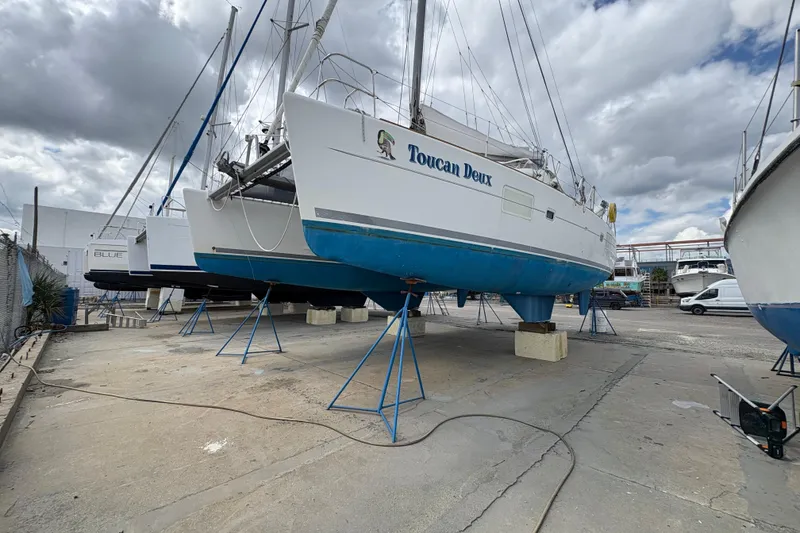 Slide: The Image of 2004 Lagoon 380 catamaran "Toucan Deux" on dry dock under cloudy sky. - 3