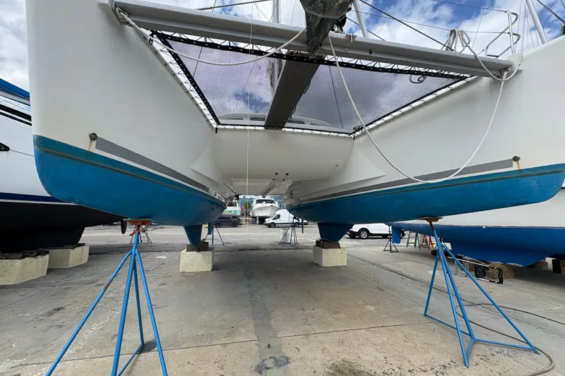 Slide: The Image of 2004 Lagoon 380 catamaran on stands, showcasing hull and underbody in a boatyard. - 4