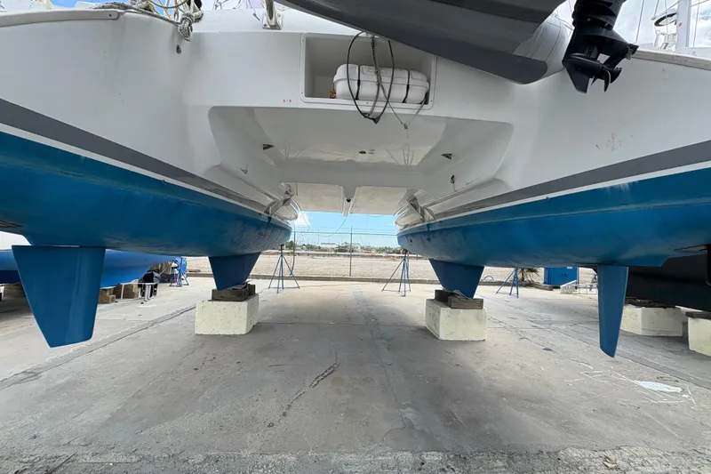 Slide: The Image of 2004 Lagoon 380 catamaran on dry dock, showcasing blue hull and twin keels. - 7