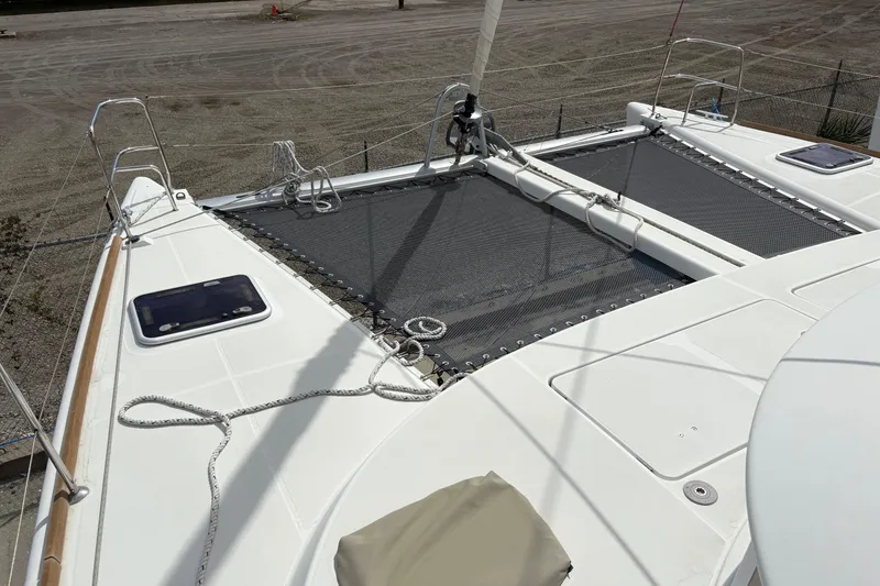 Slide: The Image of 2004 Lagoon 380 catamaran deck with netting and ropes, docked on a sandy shore. - 8