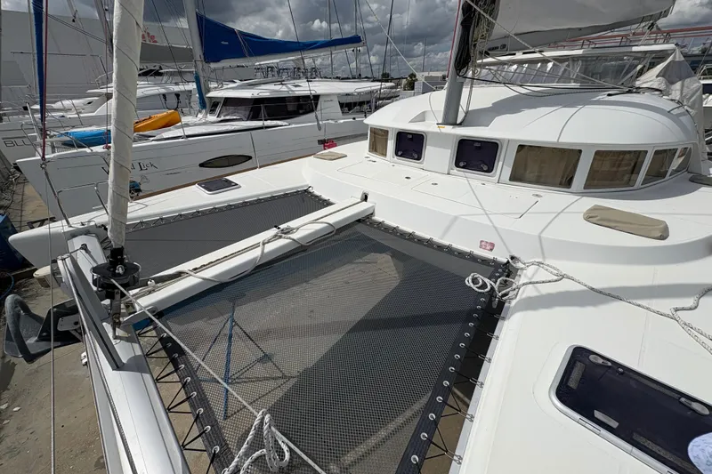 Slide: The Image of 2004 Lagoon 380 catamaran docked, featuring spacious deck and netting. - 9