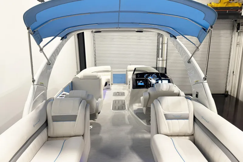 Slide: The Image of 2026 Bennington 24 LXS Fastback Sport Arch boat interior with blue canopy and luxurious seating. - 13