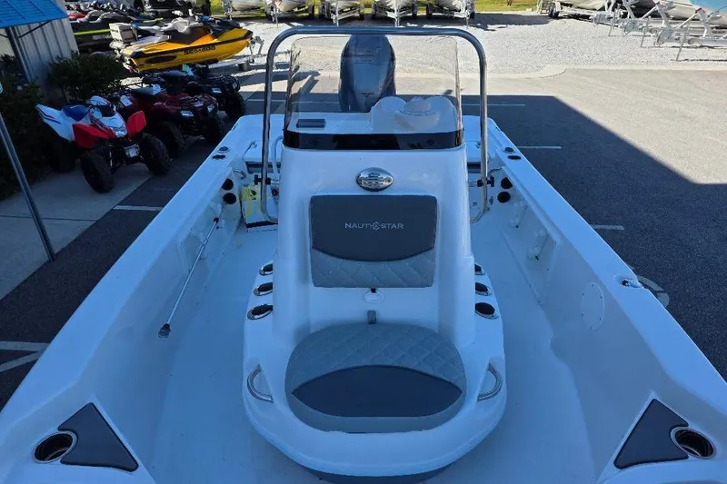 Slide: The Image of 2026 NauticStar 194 Bay boat interior with seating and console, parked near ATVs. - 8