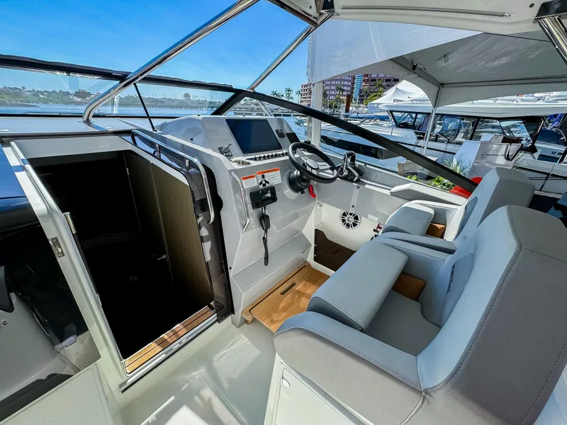 Slide: The Image of 2024 Beneteau Flyer 10 cockpit with modern controls and seating, docked at marina. - 1