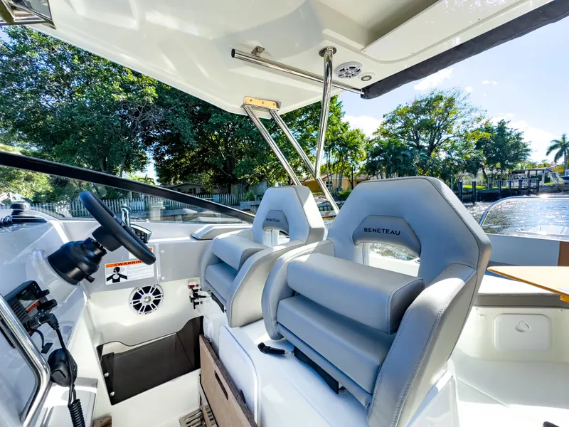 Slide: The Image of 2024 Beneteau Flyer 10 cockpit with modern seating and steering, surrounded by lush greenery. - 3