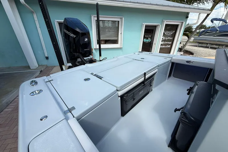 Slide: The Image of 2026 Crevalle 26 HCO boat interior with Mercury engine, docked near a turquoise building. - 16