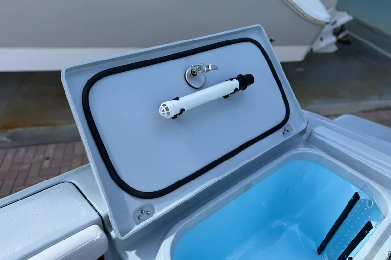 Slide: The Image of Open storage compartment on 2026 Crevalle 26 HCO boat, featuring a secure latch and blue interior. - 19