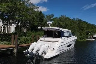 Slide: The Image of 2021 Regal 38 XO yacht docked by lush greenery. - 2