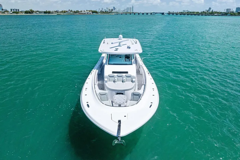 Slide: The Image of 2025 HCB 56 Suenos GIX luxury yacht on turquoise water, city skyline in background. - 4
