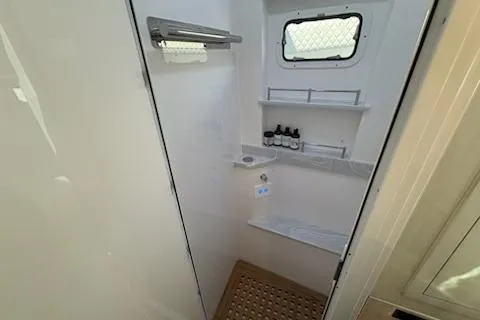 Slide: The Image of 2025 HCB 56 Suenos GIX boat bathroom with shelves, window, and toiletries. - 64