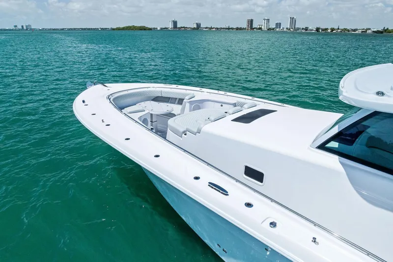 Slide: The Image of 2025 HCB 56 Suenos GIX luxury yacht on turquoise water, city skyline in background. - 7