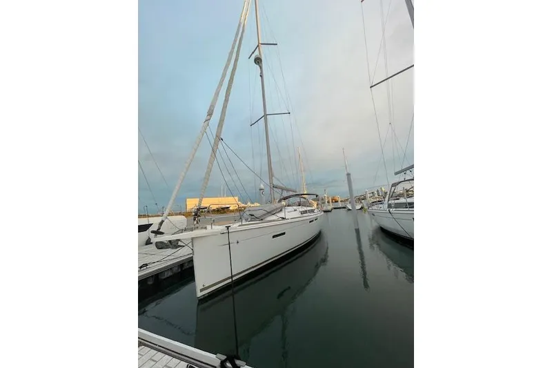 The Image of 2016 Jeanneau Sun Odyssey 419 sailboat docked at marina, calm waters, overcast sky. - 0