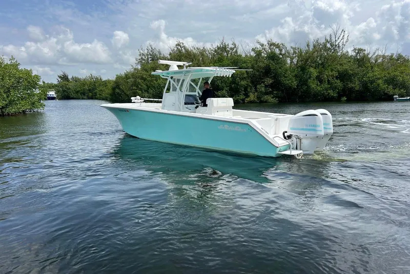 Slide: The Image of 2018 SeaHunter 31 Tournament boat cruising on a calm river with lush greenery. - 2