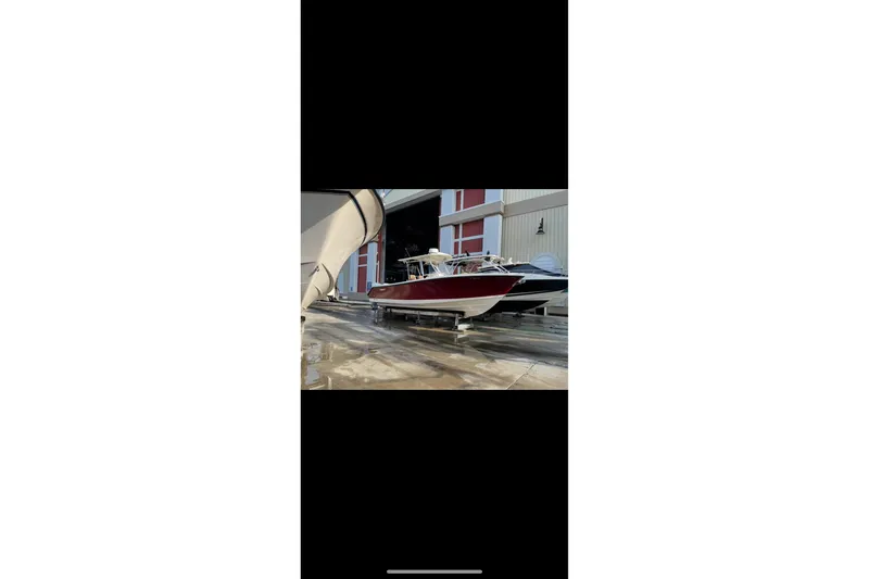 Slide: The Image of 2010 Pursuit C 280 Center Console boat in storage, red hull, parked indoors. - 3