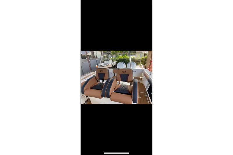 Slide: The Image of 2010 Pursuit C 280 Center Console boat with tan and black seating, docked outdoors. - 6