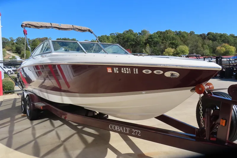 Slide: The Image of 2005 Cobalt 272 boat on trailer, parked outdoors with trees in background. - 11