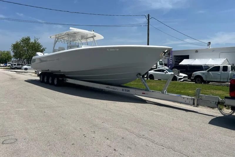 Slide: The Image of 2025 Contender 44 ST boat on trailer, parked outdoors under clear sky. - 11