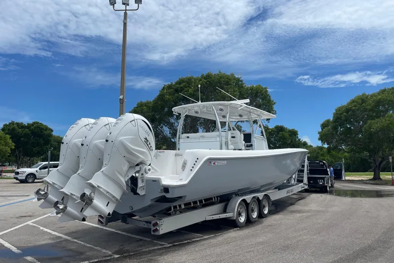 Slide: The Image of 2025 Contender 44 ST boat on trailer with triple outboard engines in parking lot. - 2