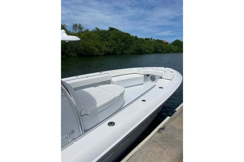 Slide: The Image of 2025 Contender 44 ST boat docked by lush greenery under a clear blue sky. - 6