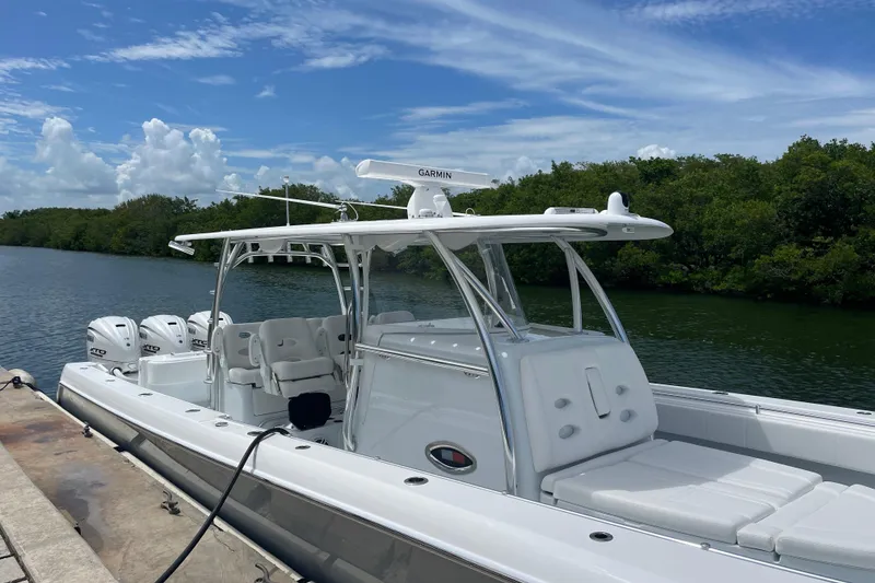 Slide: The Image of 2025 Contender 44 ST boat docked by lush greenery under a blue sky. - 7