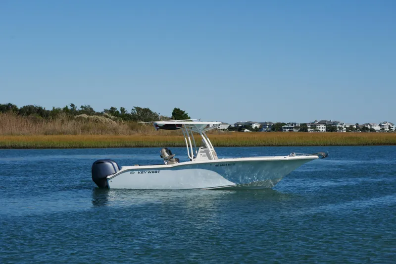The Image of 2021 Key West 244 Center Console boat on calm water, with scenic shoreline background. - 0