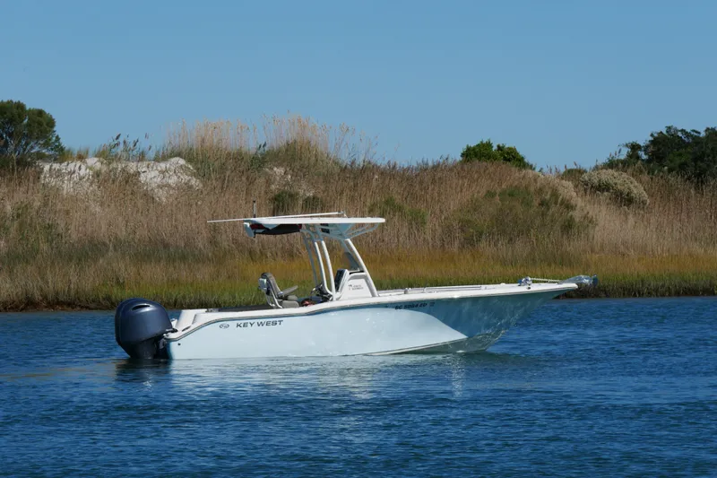 Slide: The Image of 2021 Key West 244 Center Console boat on calm water, with scenic shoreline background. - 1