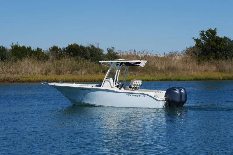 Slide: The Image of 2021 Key West 244 Center Console boat on calm water near grassy shoreline. - 4