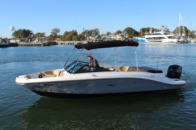 The Image of 2023 Sea Ray SPX 210 boat cruising on a calm waterway with scenic marina backdrop. - 0