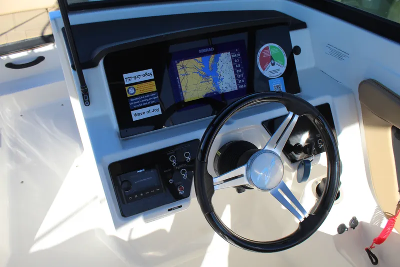 Slide: The Image of 2023 Sea Ray SPX 210 dashboard with steering wheel and navigation display. - 16
