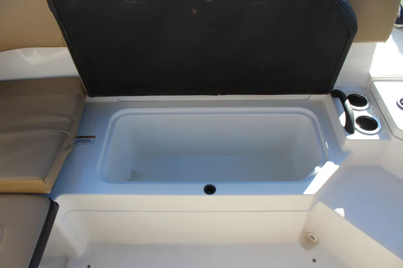 Slide: The Image of 2023 Sea Ray SPX 210 boat storage compartment with open lid and cup holders. - 24