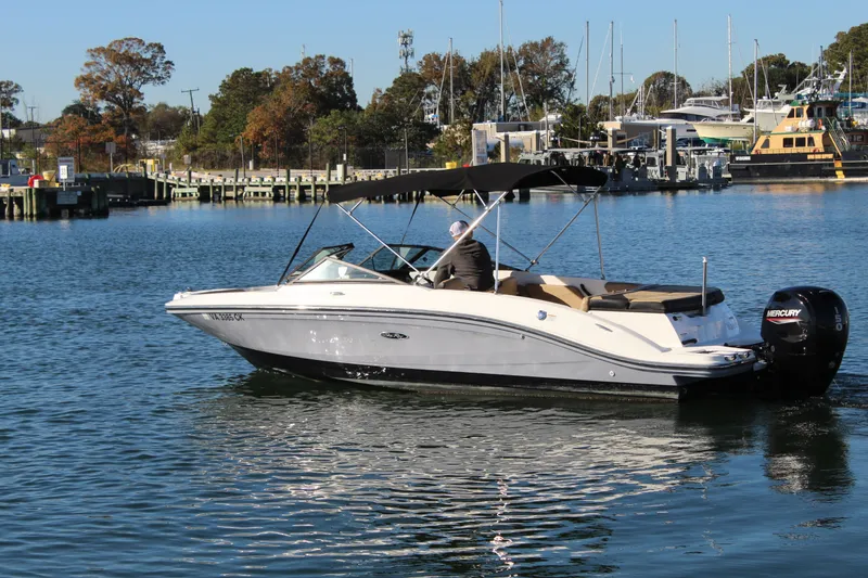 Slide: The Image of 2023 Sea Ray SPX 210 boat cruising on a calm lake near a marina. - 5