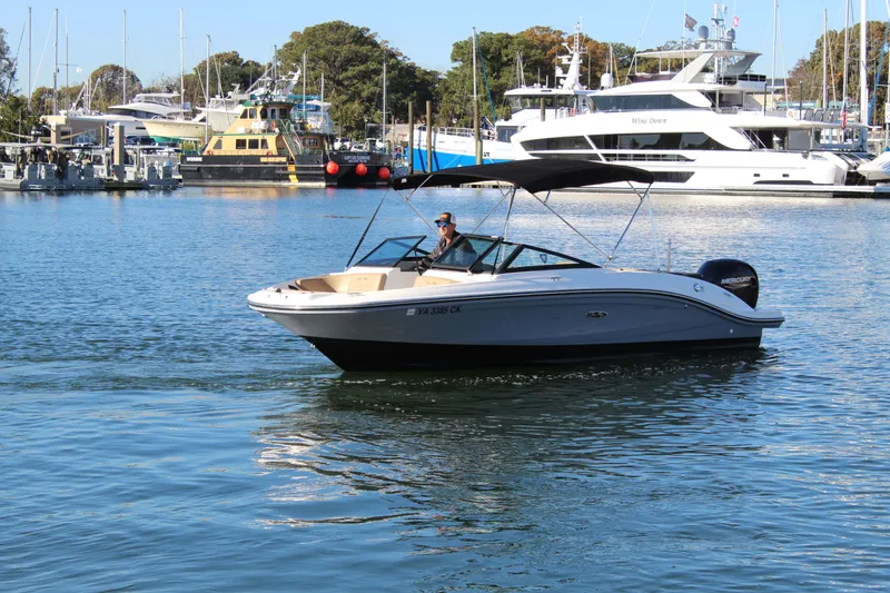 Slide: The Image of 2023 Sea Ray SPX 210 boat cruising in a marina with yachts in the background. - 7