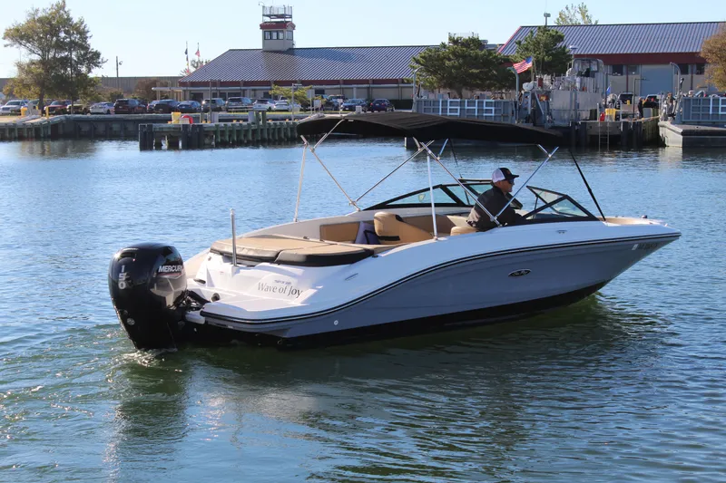 Slide: The Image of 2023 Sea Ray SPX 210 boat cruising on a calm waterway near a marina. - 9