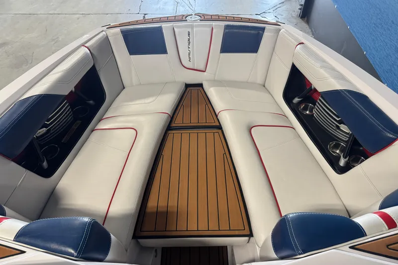 Slide: The Image of 2015 Nautique Super Air Nautique G23 interior with white, blue, and red seating, teak flooring. - 15