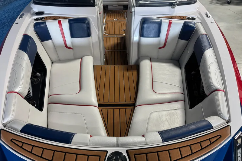 Slide: The Image of 2015 Nautique Super Air Nautique G23 interior with white, blue, and red seating, teak flooring. - 16