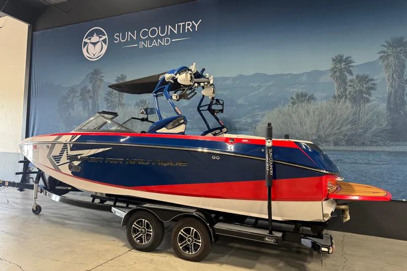 Slide: The Image of 2015 Nautique Super Air Nautique G23 boat in showroom, red and blue design, on trailer. - 3