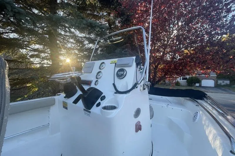 Slide: The Image of 2023 Key West 189 FS boat console with gauges, steering wheel, and trees in the background. - 5