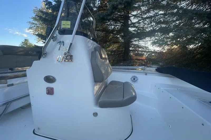 Slide: The Image of 2023 Key West 189 FS boat interior with seating and console, surrounded by trees. - 6