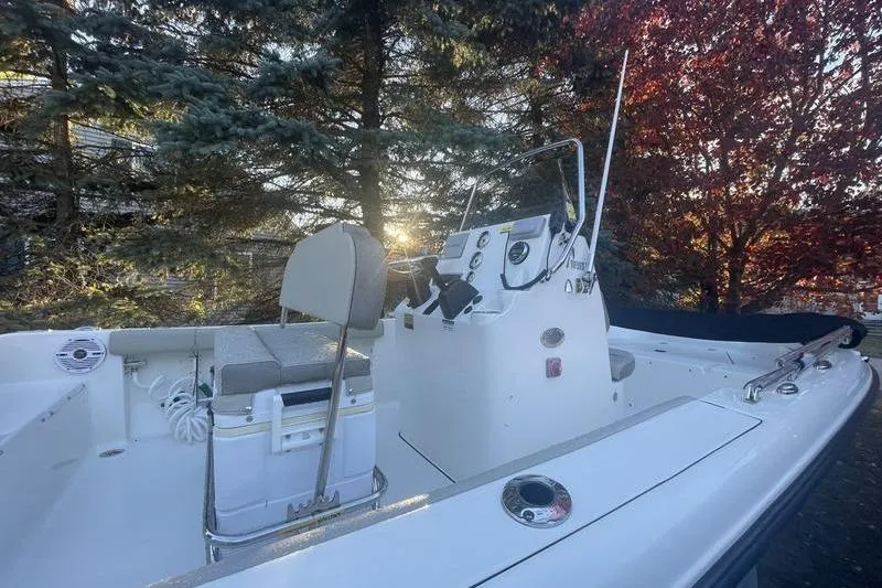 Slide: The Image of 2023 Key West 189 FS boat interior with console and seating, surrounded by trees. - 8