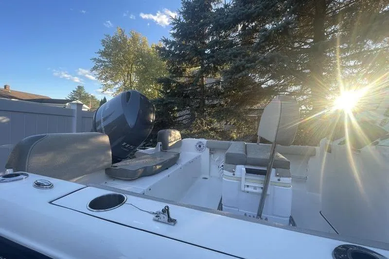 Slide: The Image of 2023 Key West 189 FS boat interior with seating, motor, and sunlight through trees. - 9