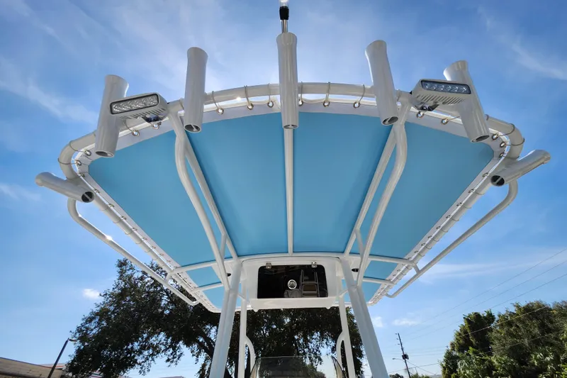 Slide: The Image of T-top of 2026 Savannah 2200 Offshore boat with blue canopy and rod holders. - 32