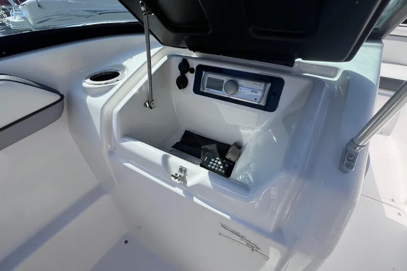 Slide: The Image of 2015 Yamaha Boats SX192 storage compartment with stereo system and cup holder. - 19