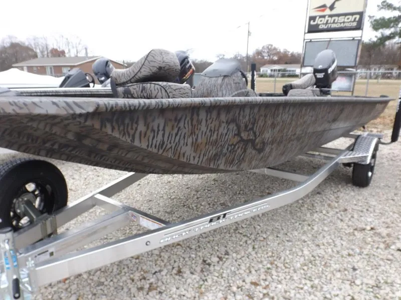 The Image of 2019 Xpress XP180 boat on trailer, camo design, parked outdoors near Johnson Outdoors sign. - 0