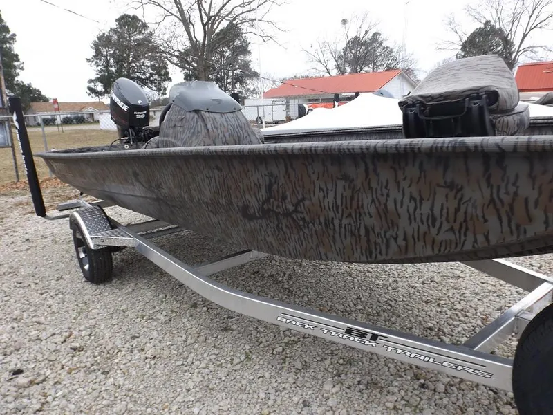 Slide: The Image of 2019 Xpress XP180 boat on trailer, camo design, parked outdoors. - 2