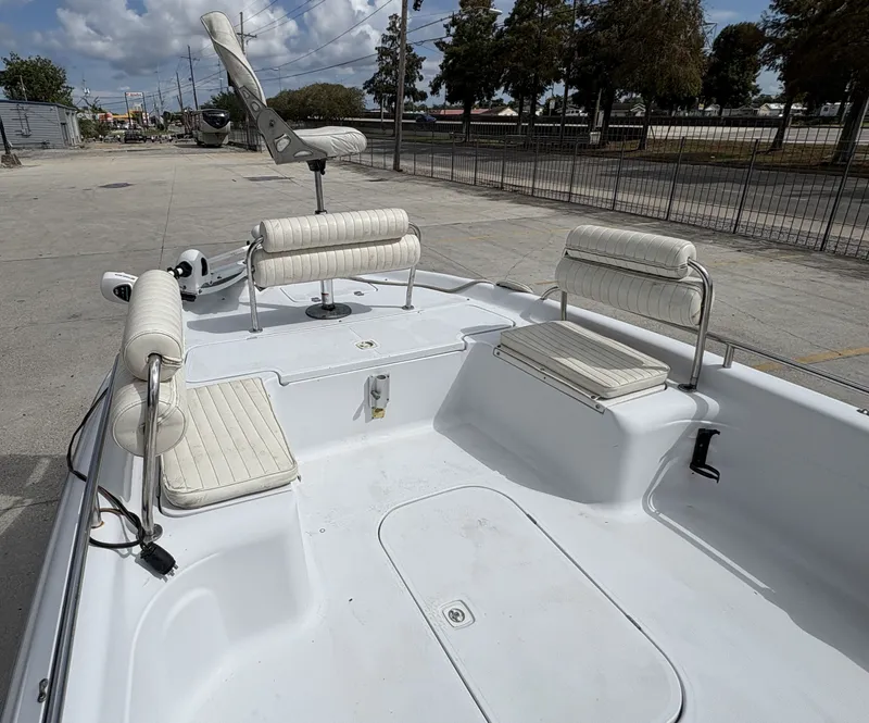 Slide: The Image of 2000 Fishmaster 23 boat with white seating and open deck, parked outdoors. - 11