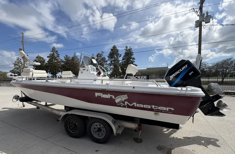 Slide: The Image of 2000 Fishmaster 23 boat with Mercury EFI engine on trailer, under cloudy sky. - 8